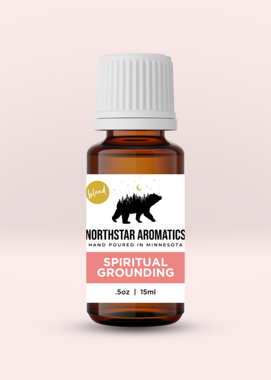 Amber glass bottle of Spiritual Grounding essential oil blend by Northstar Aromatics with white cap on soft pink background