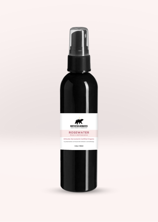 Black spray bottle with a white label showing rosewater text on a light beige background