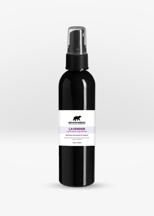 Black spray bottle with a white label displaying lavender essential oil information on a plain white background