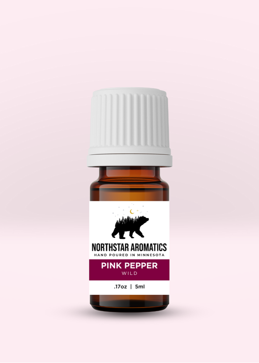 Small amber bottle of Pink Peppercorn, Wild essential oil by Northstar Aromatics on a soft pink background.