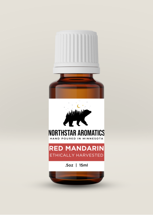 Amber glass bottle of ethically sourced Red Mandarin essential oil by Northstar Aromatics with white ribbed cap on neutral background