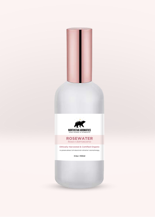 Frosted glass bottle of rosewater hydrosol by Northstar Aromatics with metallic rose gold cap on pale blush background