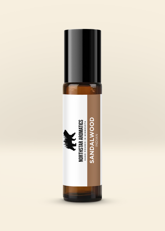 Amber glass roll-on bottle of Indian Sandalwood essential oil by Northstar Aromatics with black cap on beige background