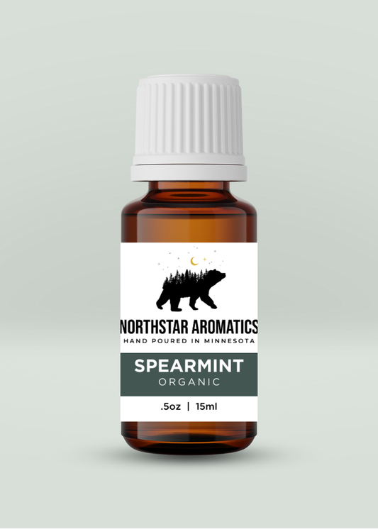 Amber glass bottle of organic Spearmint oil with white ribbed cap and Northstar Aromatics label on pale green background