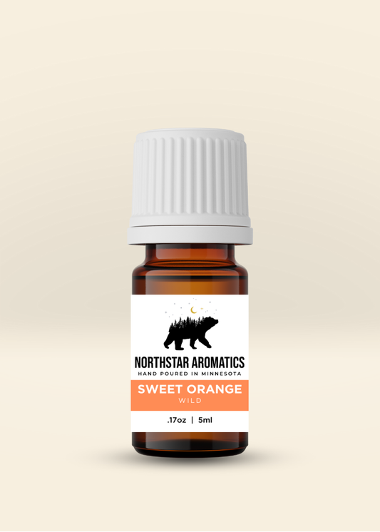 Amber bottle of Sweet Orange essential oil by Northstar Aromatics with white cap and label against beige background.