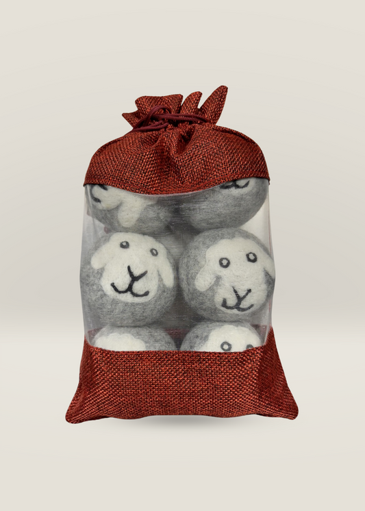 Laundry Balls in red mesh bag with handmade New Zealand wool dryer balls featuring sheep faces.