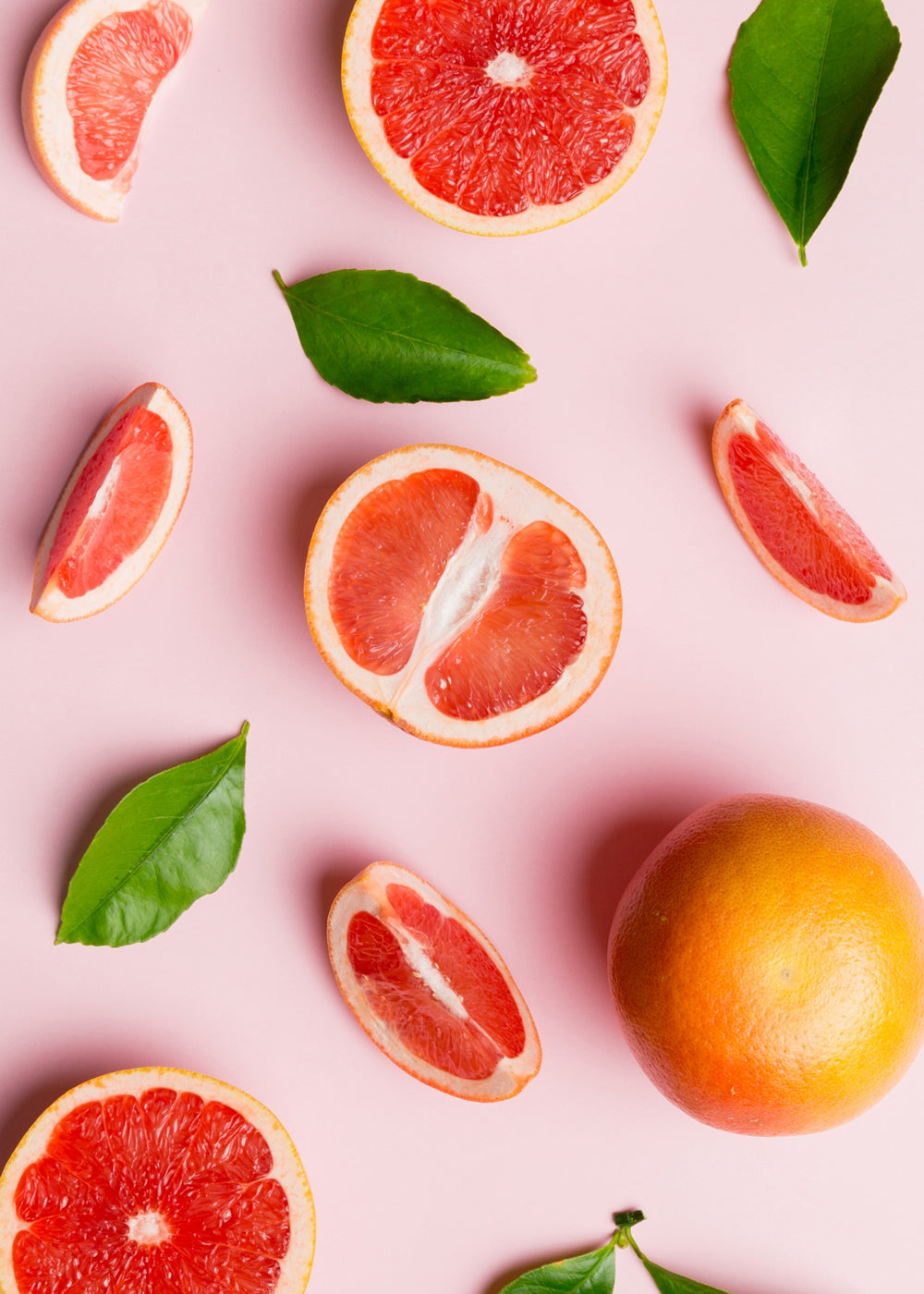 Grapefruit Splash Set with fresh grapefruit slices and green leaves on a pink background for aromatherapy.