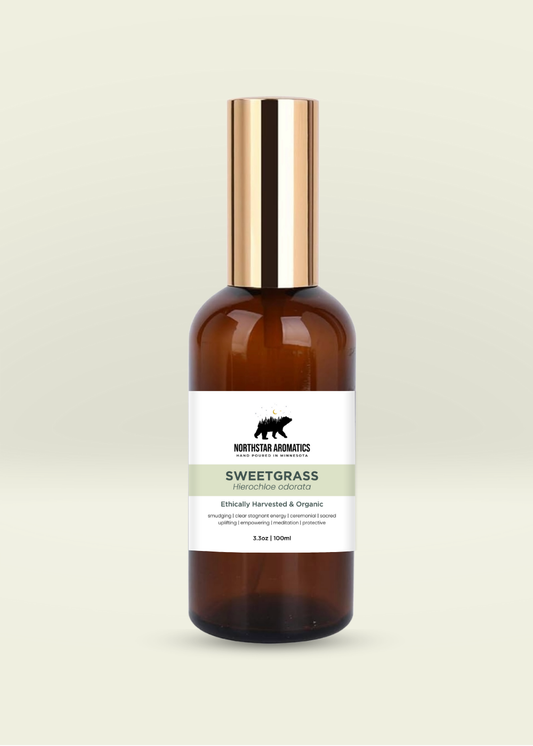 Amber glass spray bottle of organic Sweetgrass hydrosol by Northstar Aromatics on pale neutral background