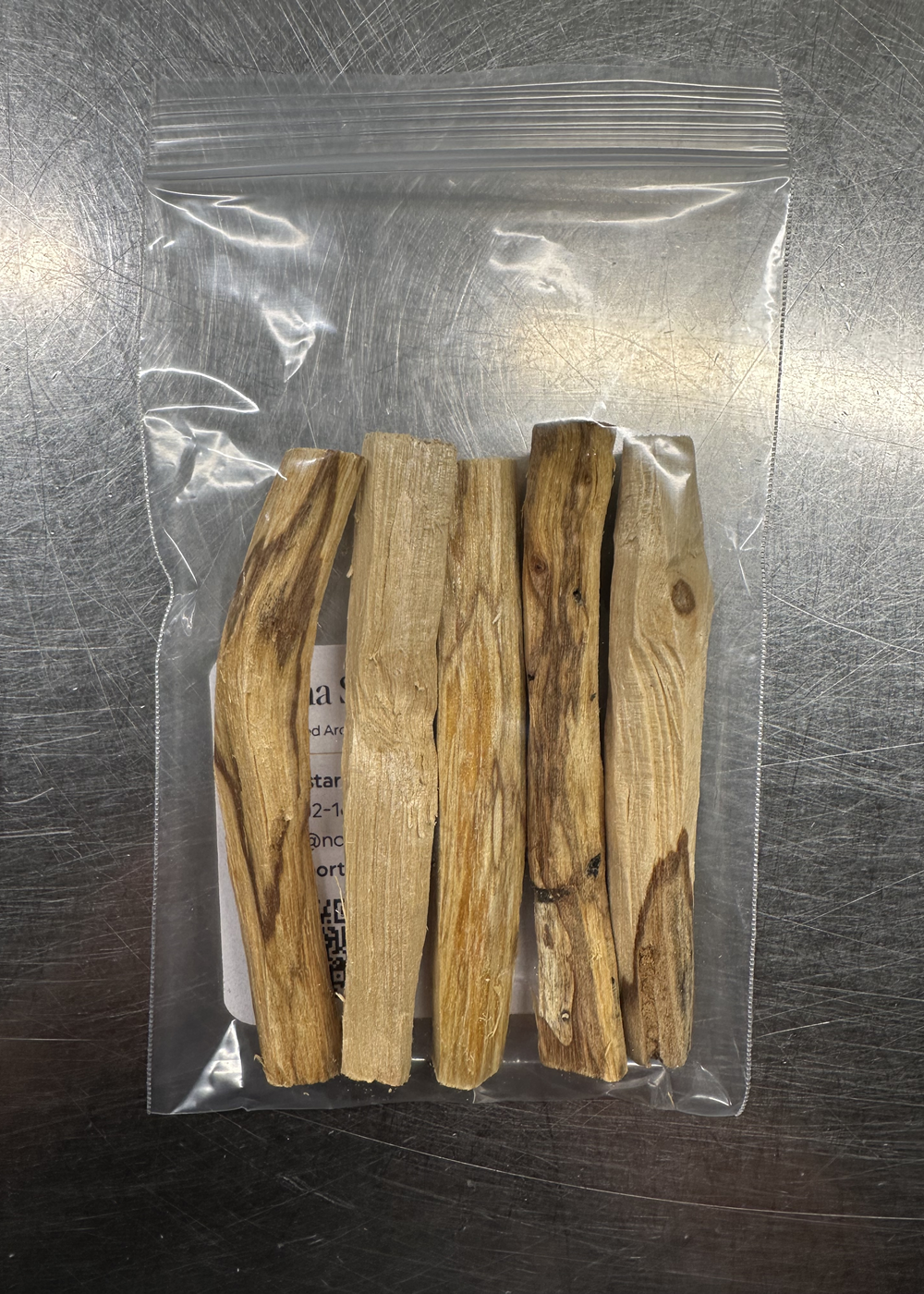 Palo Santo Smudge Sticks packaged in a clear resealable bag on a metal surface, natural cleansing wood sticks.