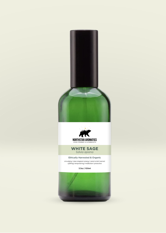 Green glass spray bottle of organic White Sage hydrosol by Northstar Aromatics on pale cream background