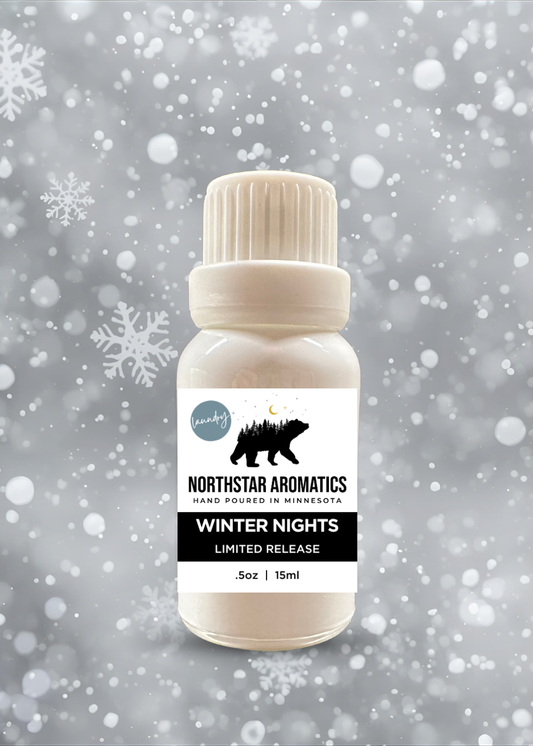Small bottle of Winter Nights limited edition laundry oil with snowy background and falling snowflakes